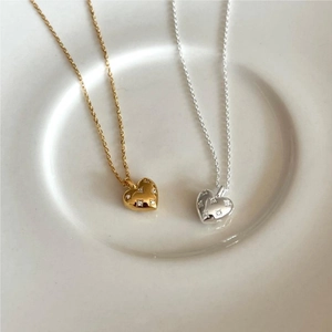 Close-up of gold and silver heart pendants with micro-pave cubic zirconia on ceramic tray