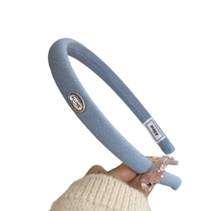 Sky blue floral fabric headband with silver oval metal tag and minimalist design