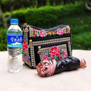 Detail view of ethnic embroidery handbag with colorful floral patterns and metal zippers