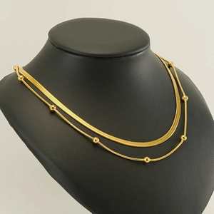 Close-up of golden double-layered necklace featuring snake chain and bead chain details