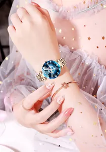 Detail of starry blue faceted glass dial and rose gold metal strap on woman wrist