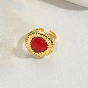 Close-up of gold adjustable ring featuring a red round gemstone and dotted texture