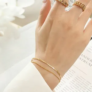 Elegant gold double-layer snake chain bracelet with sparkling rings on model wrist