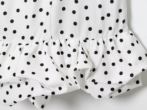Gros plan sur tissu blanc à pois avec bords à volants détaillés et texture de couture