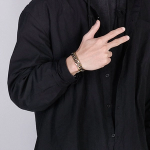Classic stainless steel Cuban link bracelet for men in vintage gold finish on a model's wrist
