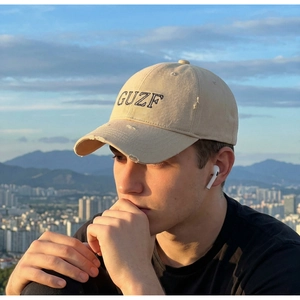 Detailed close-up of distressed vintage beige baseball cap with GUZF embroidery