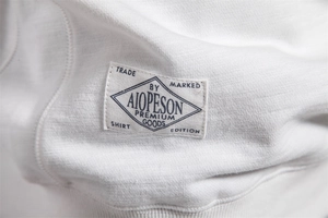 Detail of premium white cotton sweatshirt showing woven fabric texture and stitched brand label