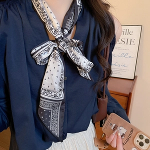 Detail of silk scarf necklace with black and white paisley print tied around the neck