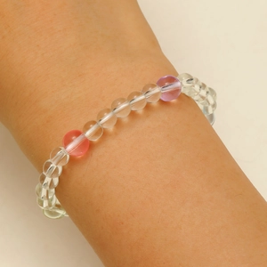 Détail d'un bracelet en perles de cristal transparent, rose et violette au poignet