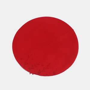 Dettaglio del basco in maglia rossa con delicate decorazioni floreali di perline in tinta
