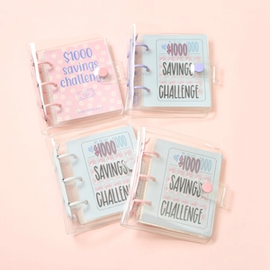 Flat lay of PVC transparent $1000 savings challenge binders with colorful snap buttons