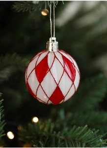 Vue détaillée d'une boule de Noël à motifs de losanges rouges et blancs pailletés