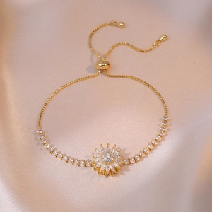 Detail of adjustable gold sunflower bracelet with cubic zirconia on silk background