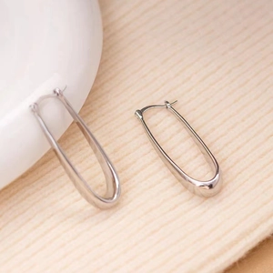 Detail of silver U-shaped hoop earrings showing metallic luster on a ceramic edge