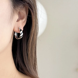 Model wearing stylish zebra print enamel hoop earrings with a sleek silver finish
