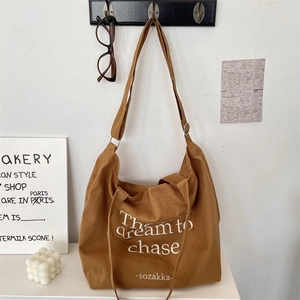 Detail of caramel brown canvas tote bag with adjustable strap and printed text