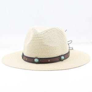 Dettaglio cappello in paglia beige con cinturino in pelle marrone e borchie turchesi