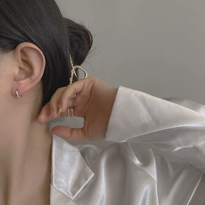 Detail shot of elegant silver hoop earrings and gold twisted hair clip on model
