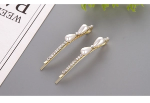 Detailed view of two gold pearl hair clips with rhinestones and elegant teardrop charms