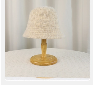 Close-up of beige knitted bucket hat texture on a wooden stand with soft lighting