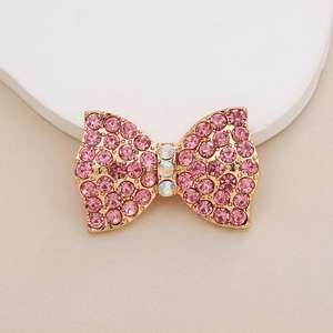 Detail of gold-plated bow charm with pink crystals and shimmering rhinestone center