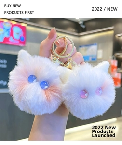 Detail of plush cat ear pom-poms with starry resin eyes and golden keychain