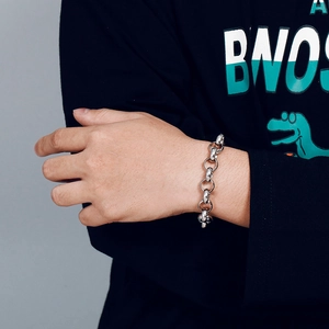 Close-up of a silver stainless steel rolo chain bracelet on a male wrist in punk style