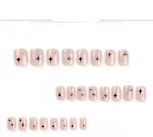 Detail view of pink glitter press-on nails with black stars and rhinestone accents