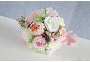 Detailed view of bridal bouquet with pink roses, silk ribbons and green leaves