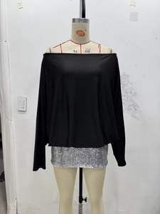 Detail view of a black off-shoulder long sleeve top with a silver sequin mini skirt set