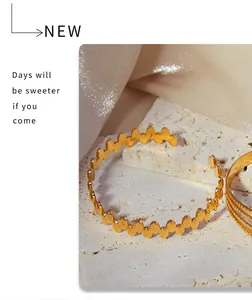 Detail of 18K gold-plated titanium geometric wavy cuff bracelet on a white stone base