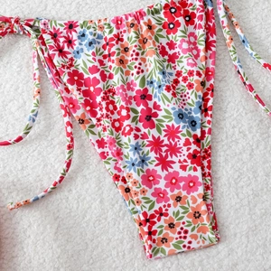 Detailed close-up of colorful floral side-tie bikini bottoms on a soft white background