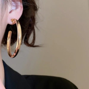 Close-up of polished gold chunky hoop earring worn by a model for a vintage look