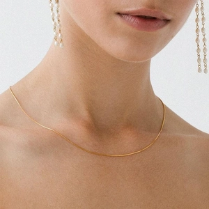 Gold stainless steel snake chain necklace with elegant long pearl drop earrings on a model