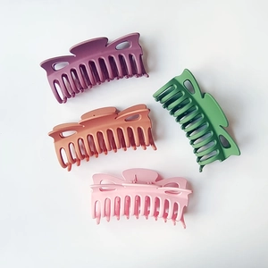 Top view of four 12cm matte bow hair claws in purple, orange, green, and pink colors
