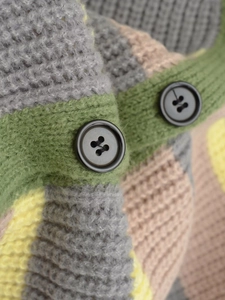 Close-up of color-block knit cardigan featuring matte black resin buttons and thick texture