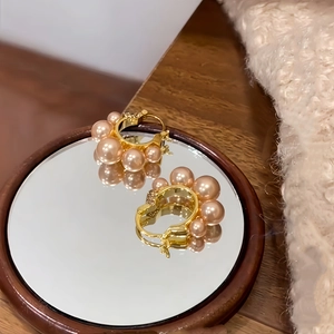 Elegant gold plated flower pearl hoop earrings on a vintage mirror surface
