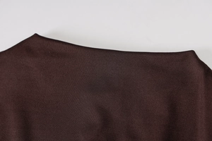 Detailed macro view of dark coffee knitted fabric and neckline stitching on the jumpsuit