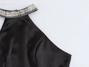 Close-up of elegant black satin halter neck dress featuring intricate silver sequin trim