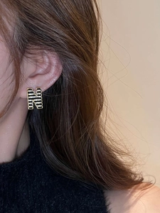 Macro detail of the 18K gold plated H-shaped earring with black enamel and zircons