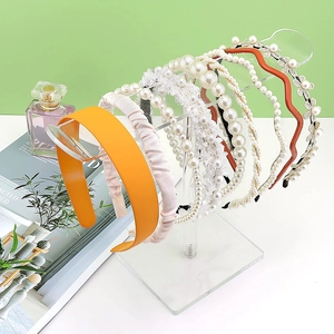 Various styles of headbands and hair accessories on a transparent acrylic display stand