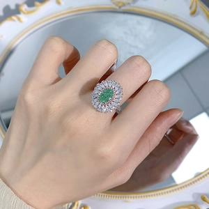 Detailed close-up of oval green gemstone ring with pavé diamond halo on silver band