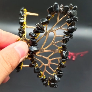 Detail of handcrafted gold butterfly hair clip featuring black natural crystal stones