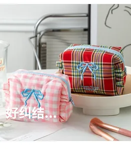 Close-up of cute plaid makeup bag with blue bow embroidery and ruffled edge details