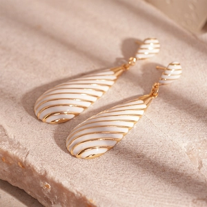 Macro shot of gold zebra stripe earrings with white enamel on a natural stone base