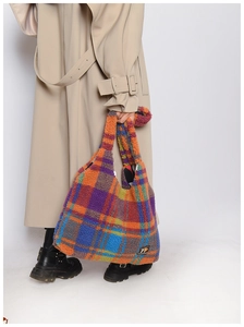Detail of colorful plaid plush tote bag showing soft texture and fashion logo label