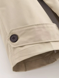 Dettaglio del polsino del trench kaki con fibbia e trama del tessuto in twill