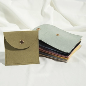 Detail of colorful microfiber jewelry pouches with gold snap buttons on silk background