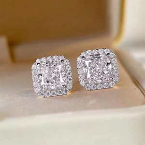 Close-up of pink and clear square halo stud earrings set in a beige jewelry box