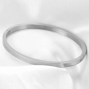 Polished silver stainless steel minimalist bracelet resting on soft white silk fabric